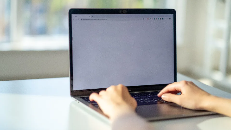 Hands typing on a laptop at a bright white desk