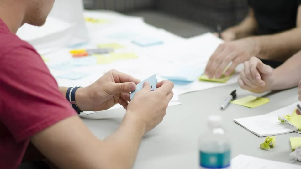 Hands sorting sticky notes on a table during a planning session