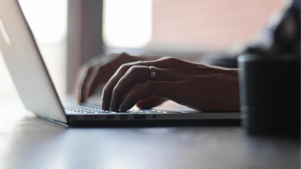 Hands typing on a laptop keyboard