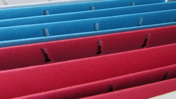 Blue and red hanging file folders in a drawer